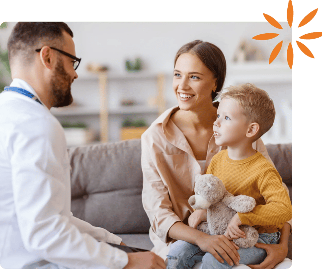 Pediatrician talking with a caregiver and child holding a stuffed animal.