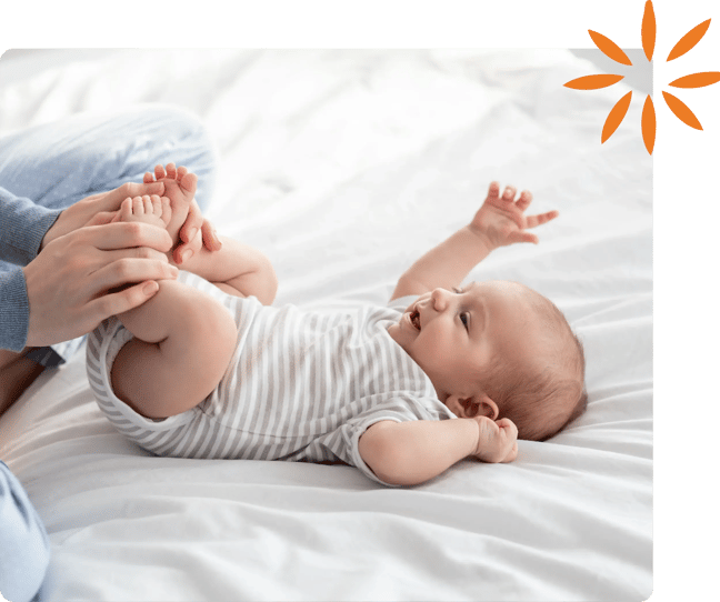 Caregiver gently holding a smiling baby's feet during playtime.