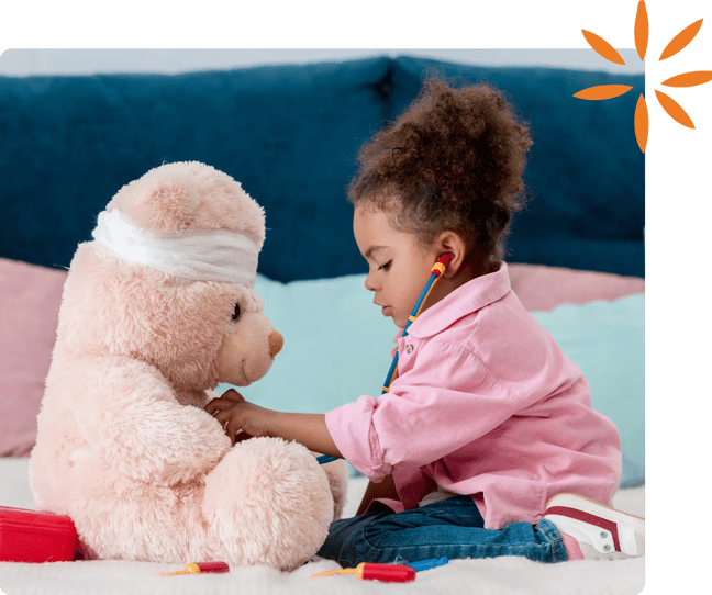 Child using a toy stethoscope to examine a teddy bear.