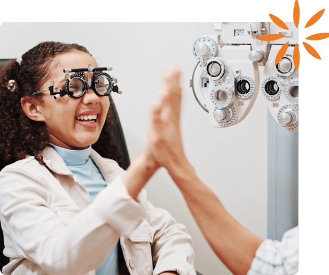Child wearing vision testing lenses and high-fiving a healthcare provider.