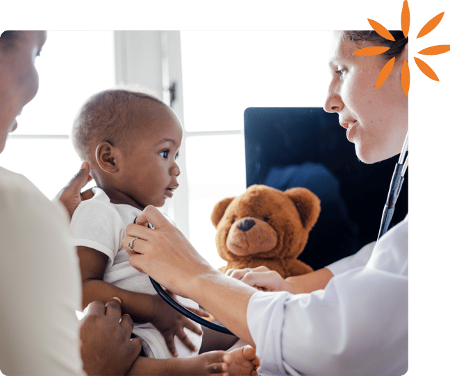 Pediatrician examining a baby while a caregiver looks on.